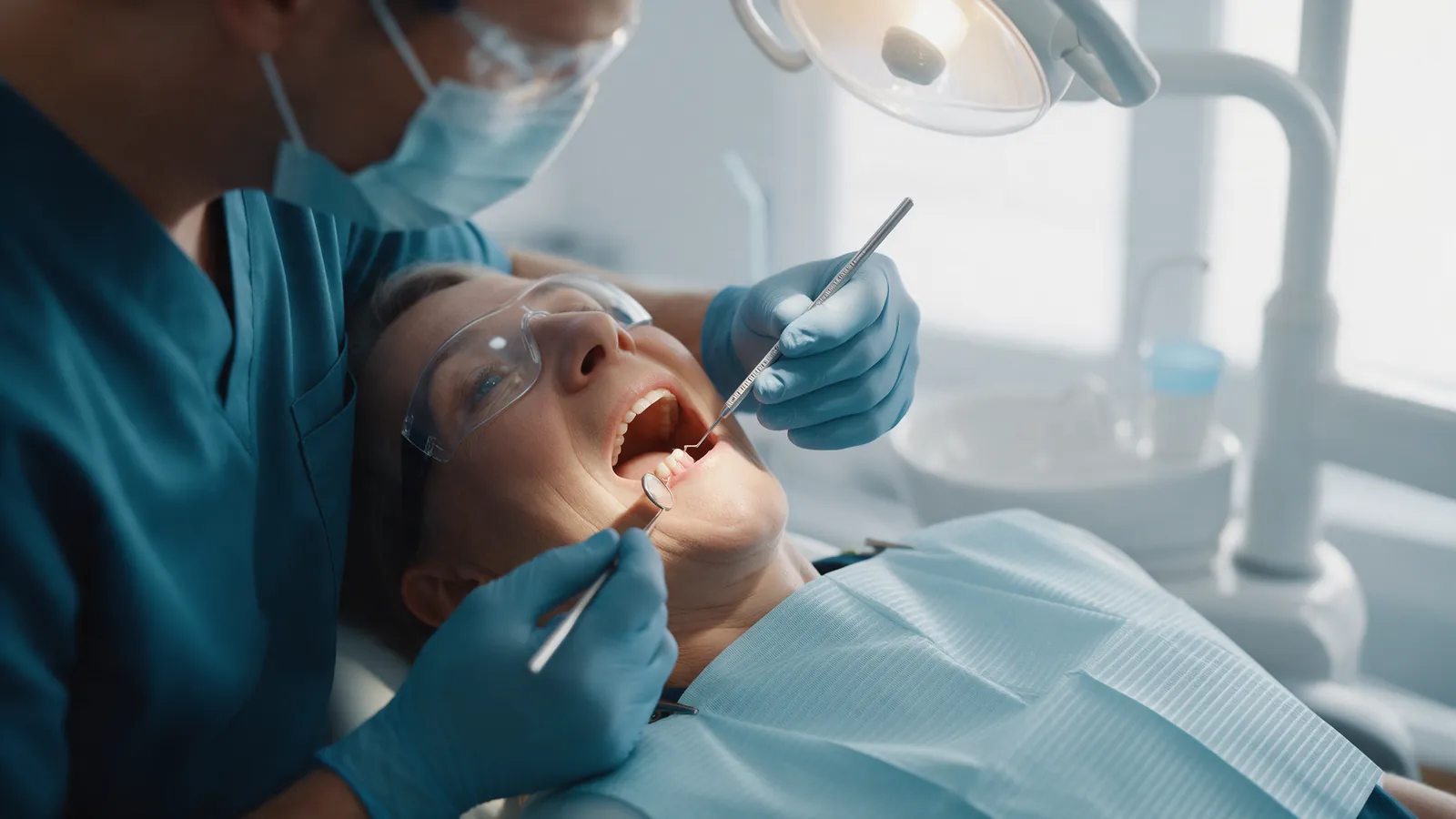 In the chair, the clinician measures periodontal pocket depth with a graduated probe.